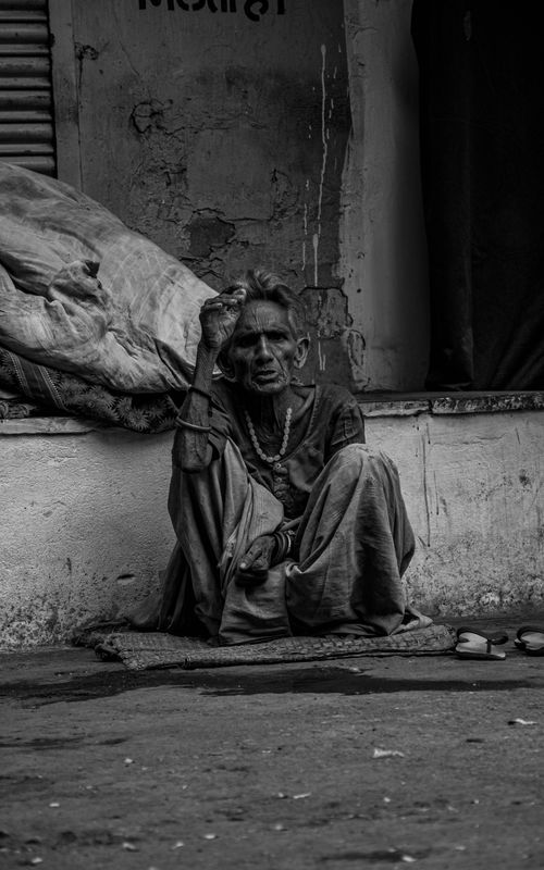 Free A senior man seated on a street corner in Udaipur, India, evoking a sense of solitude. Stock Photo
