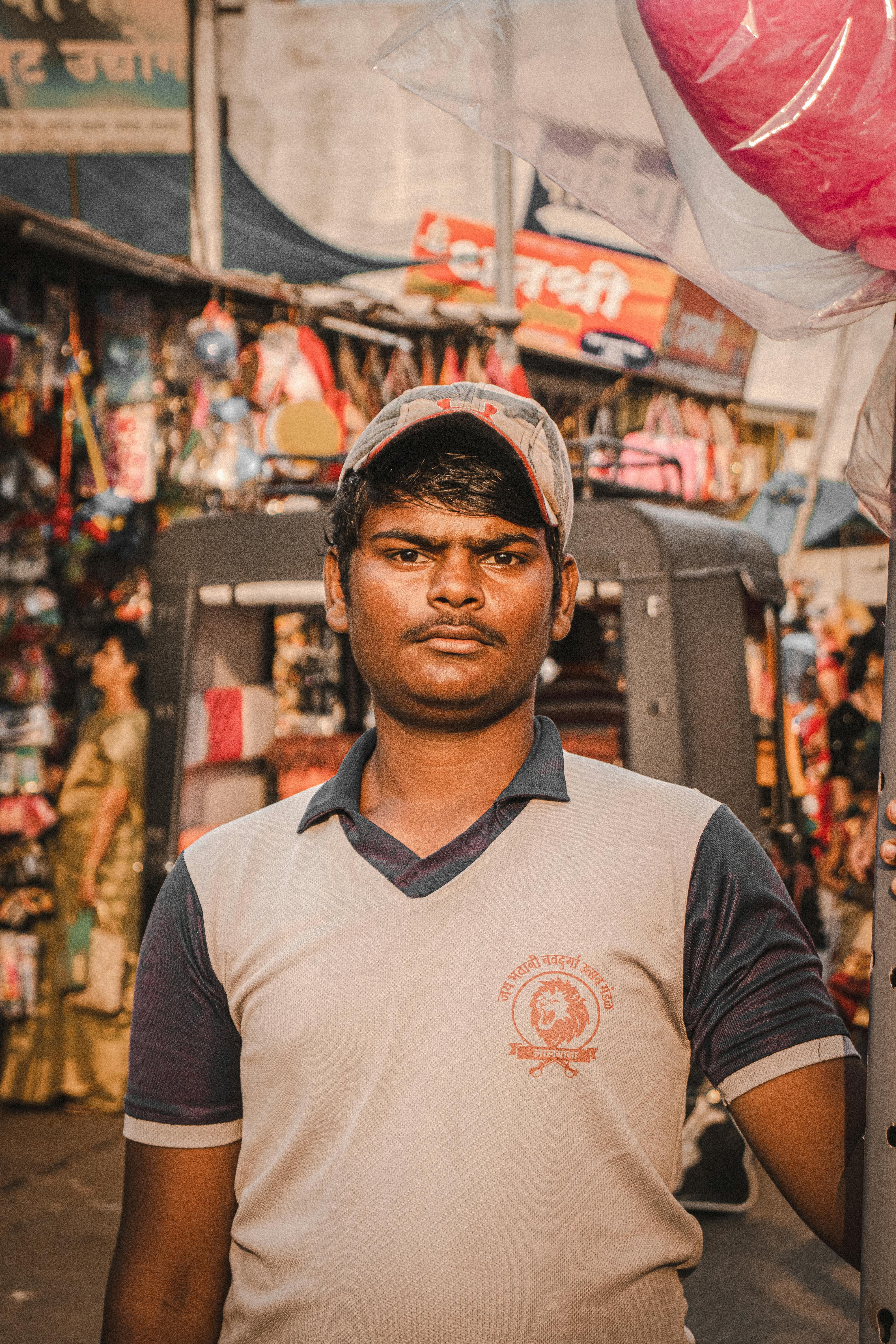 A South Asian man in a market wearing a cap, epitomizing urban life.