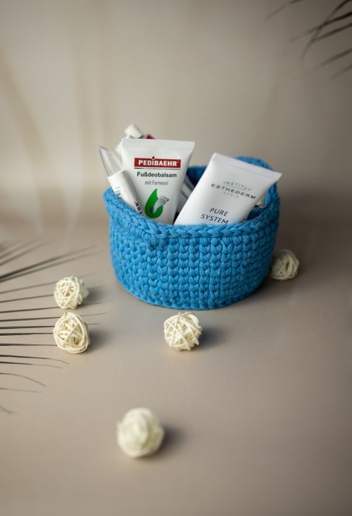 Free A blue woven basket containing skincare products with decorative spheres on a neutral background. Stock Photo