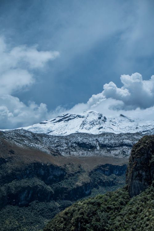 Free Scenic view of snowcapped mountains with lush valleys under a cloudy sky. Stock Photo