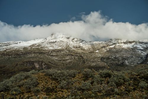 Free Snow-covered mountain range with clouds above and rugged terrain below, capturing natural beauty. Stock Photo