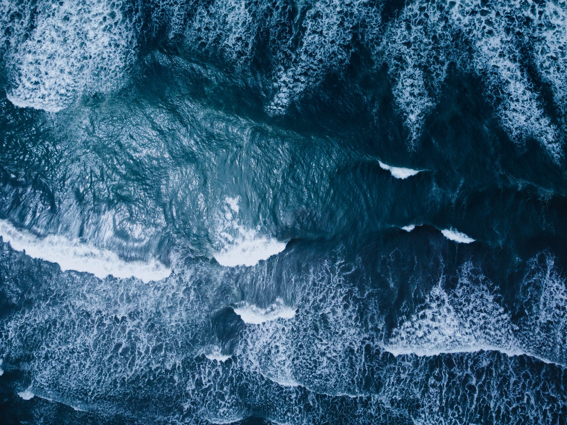 A stunning aerial shot of ocean waves crashing onto the shore, showcasing nature's power and beauty.