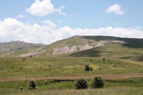 Free A breathtaking view of rolling hills and mountains under a bright blue sky. Stock Photo