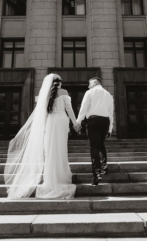 Back View of a Bride and Groom Walking Up the Stairs and Holding Hands 