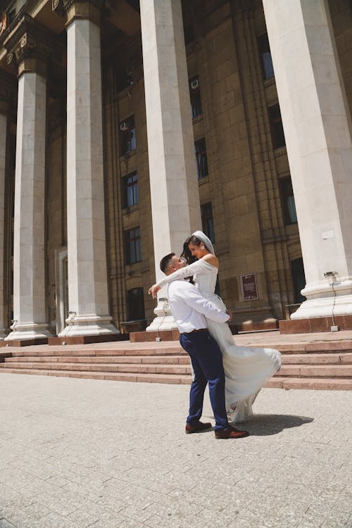 Newlyweds Hugging near Monumental Columns