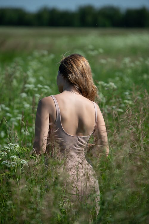 Young Blonde Woman in Summer Strap Dress Standing in a Meadow