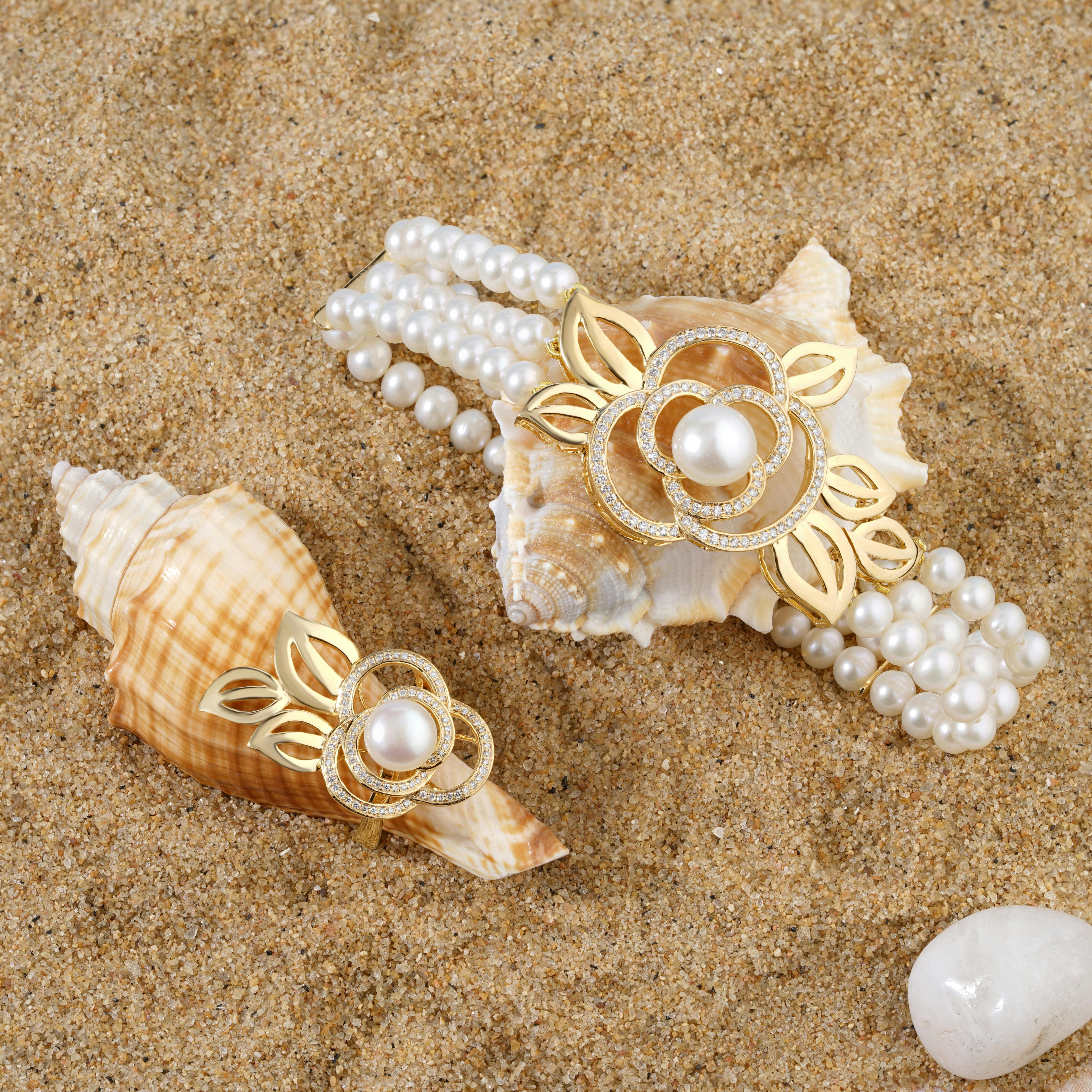 gold ring with pearl and pearl bracelet with gold flower on the beach