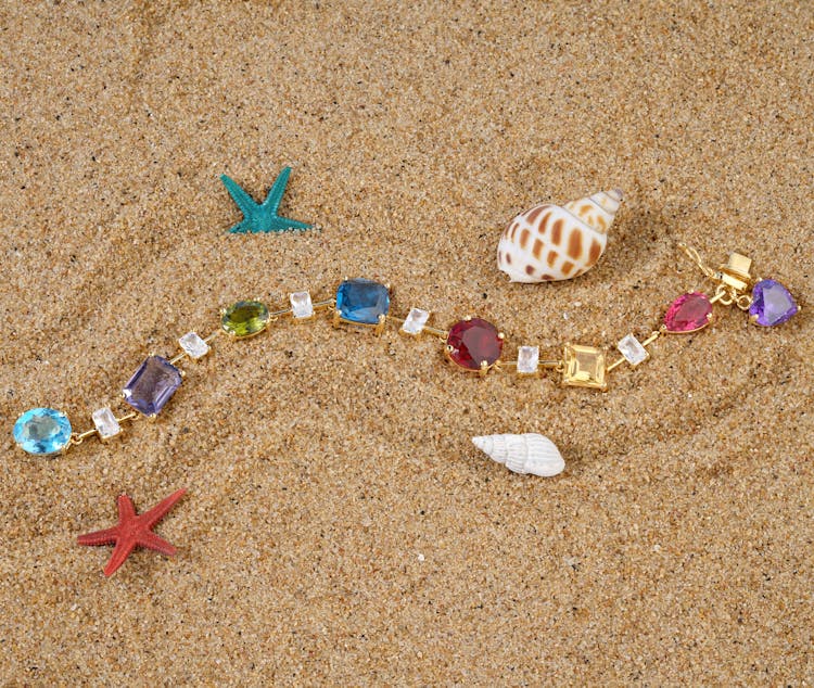 Gold Bracelet With Colorful Zircons On The Sand Among Seashells And Starfish