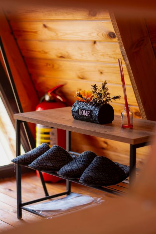 Free Wooden interior with slippers, flowers, and a home sign. Warm and inviting atmosphere. Stock Photo