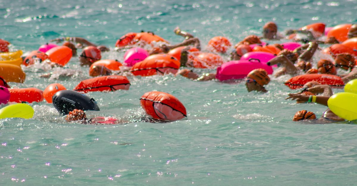 A dynamic group of swimmers with colorful lifebuoys in Bacalar Lagoon, Mexico, engaged in a summer swimming race.