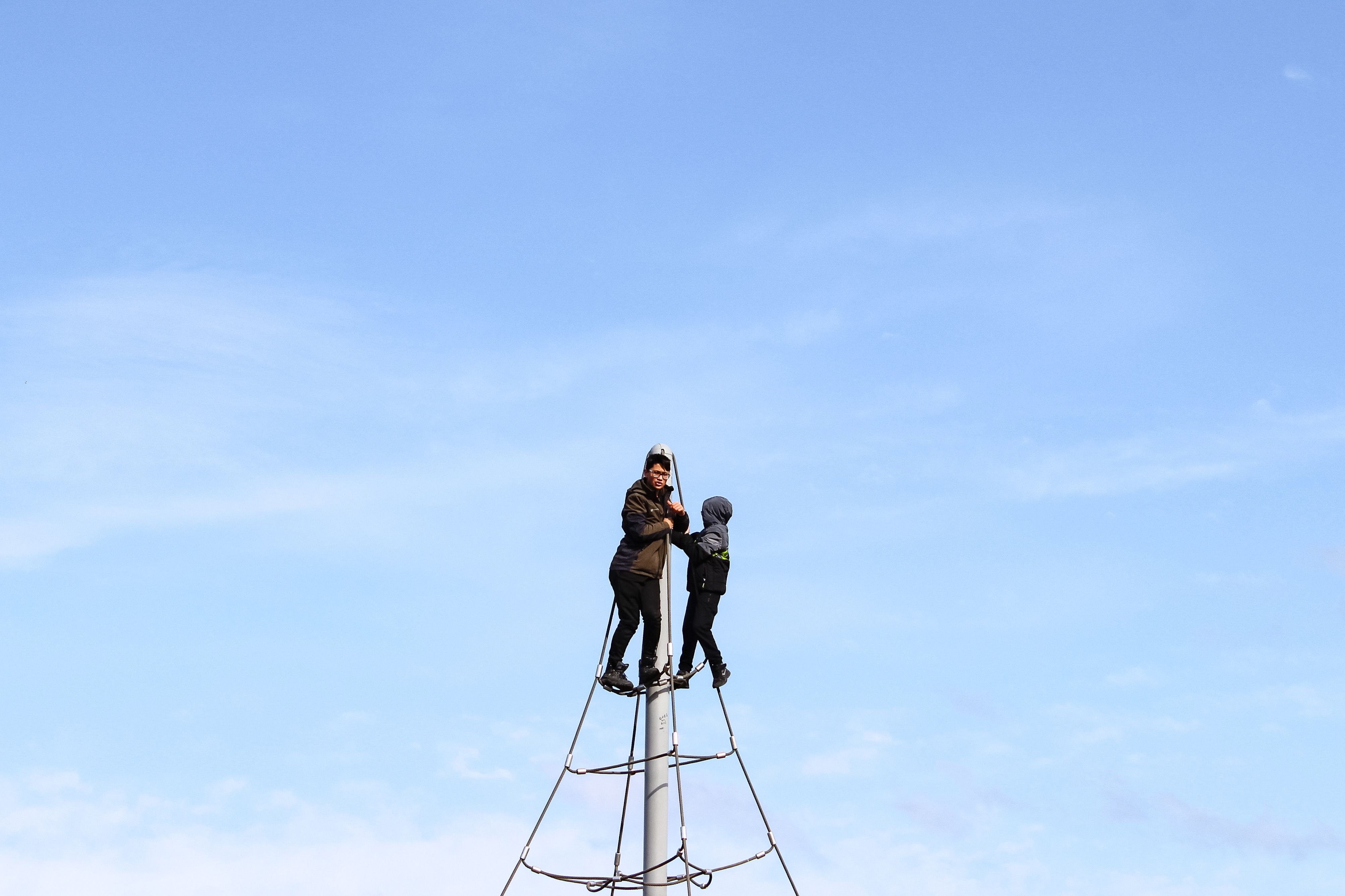 Two people standing on top of a metal pole · Free Stock Photo