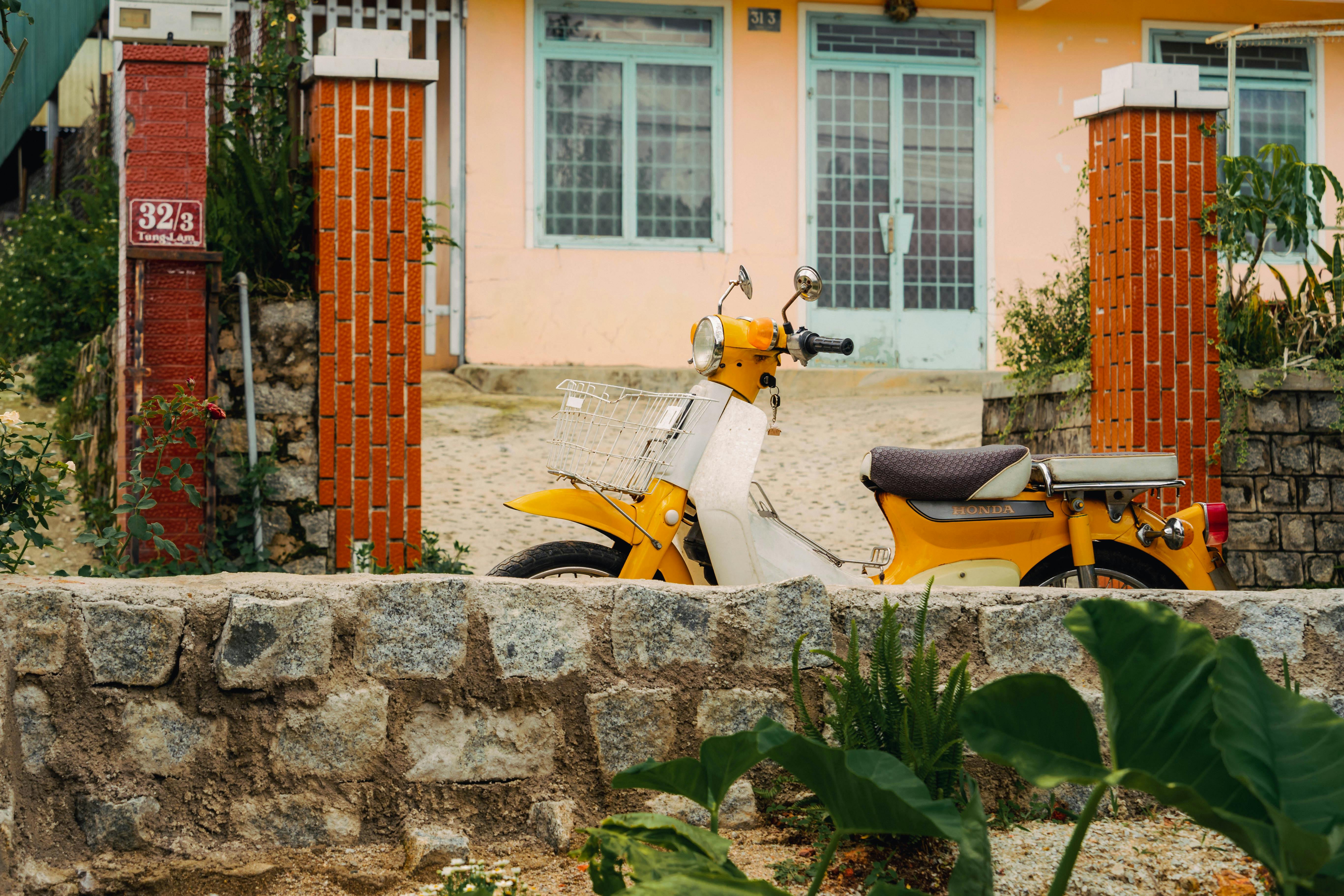 Bright yellow motorbike parked outside a charming Vietnamese home in Dalat, Vietnam.