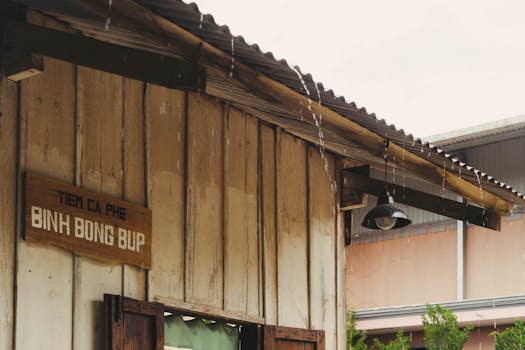 A rustic coffee shop roof dripping with rain, vintage sign visible.