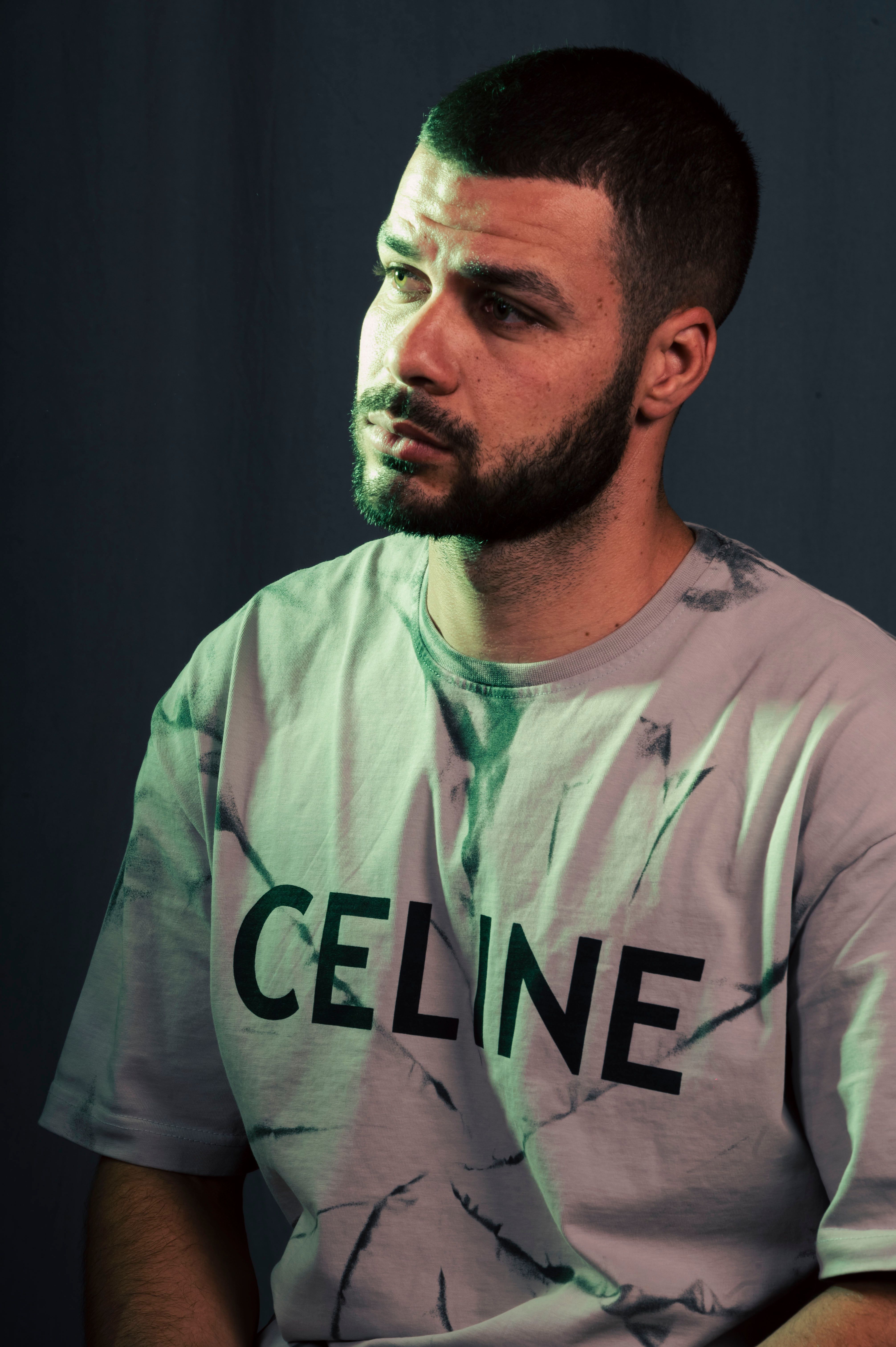 Styled portrait of a man with a beard wearing a Celine shirt, captured with unique lighting.