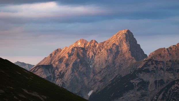 Stunning view of the Austrian Alps with a majestic mountain peak illuminated by the sunset glow.