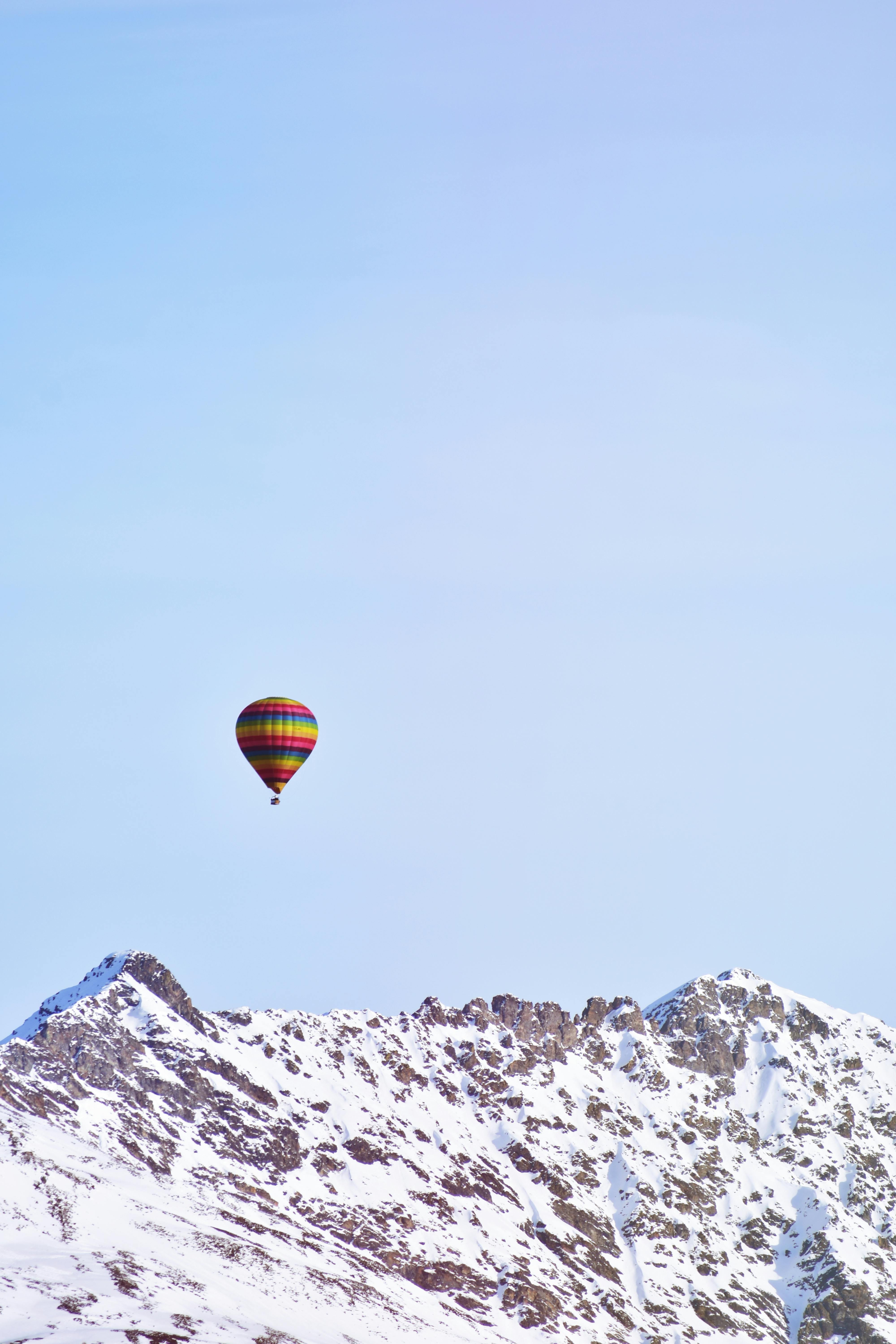 flying hot air balloon above snow covered mountain