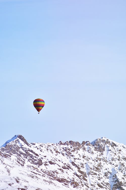 Flying Hot Air Balloon Above Snow Covered Mountain