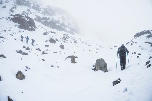 Free Hikers trekking through snowy mountainous terrain in winter, capturing the essence of adventure and exploration. Stock Photo