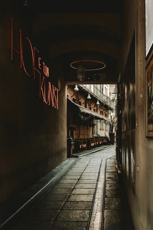 Free A narrow urban alley illuminated by neon lights and ambient evening tones, capturing the essence of city life. Stock Photo