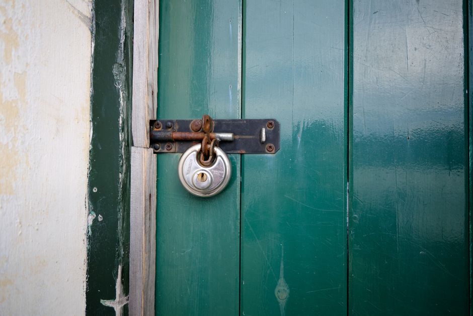 Close-up of a locked green wooden door with a metal padlock in Keswick, England.
