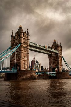 Iconic Tower Bridge spanning the River Thames under dramatic clouds in London, UK.
