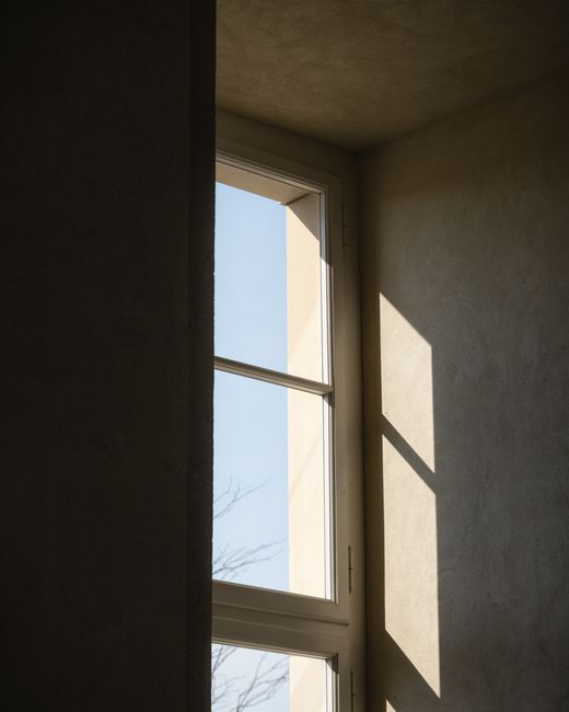 A serene, sunlit window creates minimalist shadows in a modern interior space.