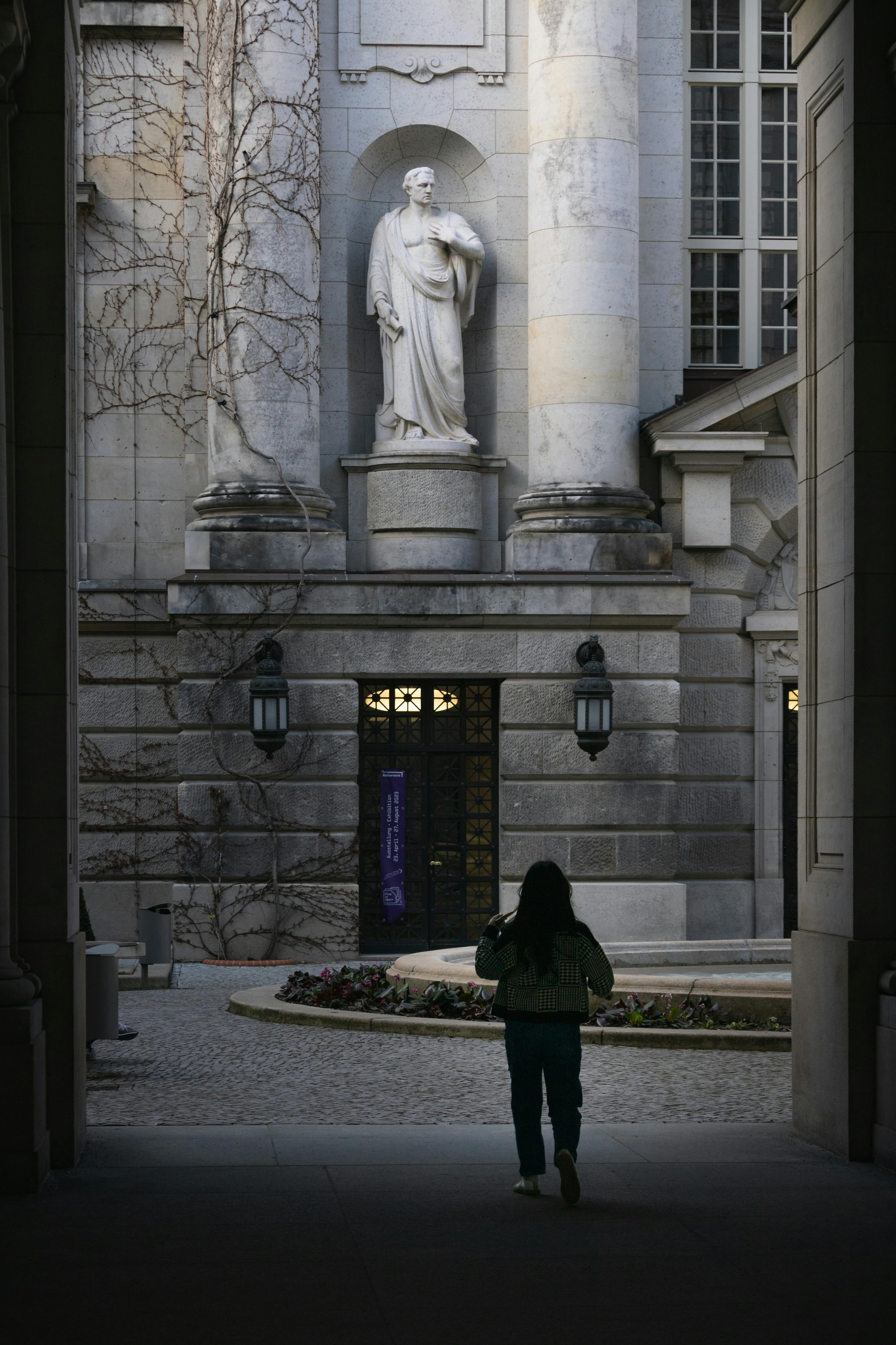 a woman walks through an archway in front of a statue