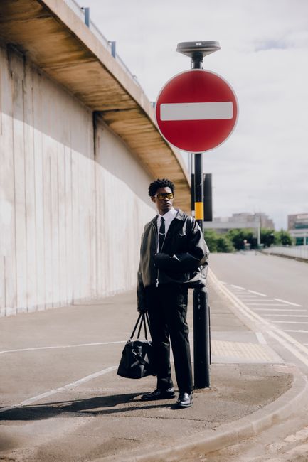 Man in urban setting with bag, showcasing trendy fashion style.