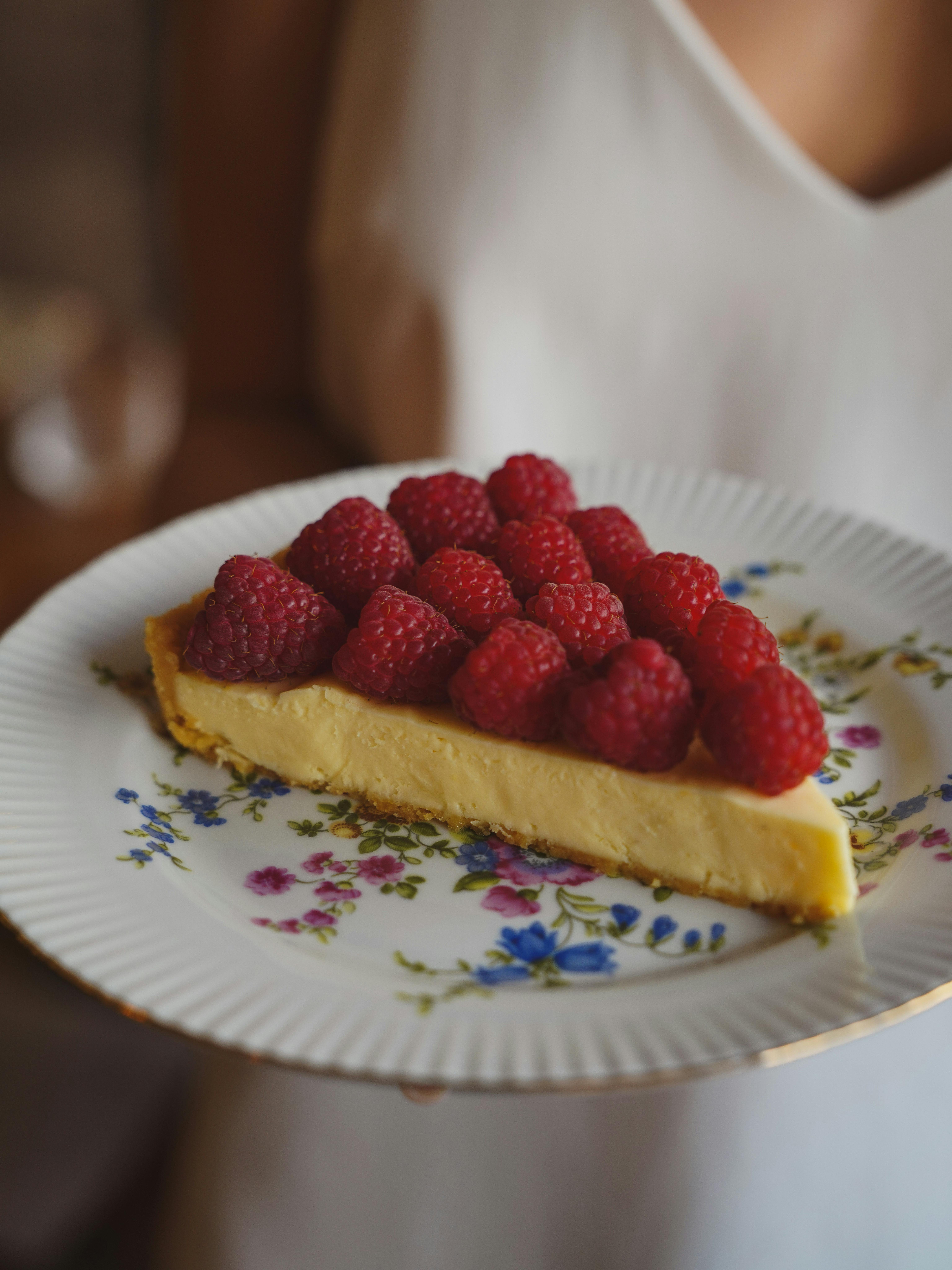 A slice of raspberry tart on a floral plate, perfect for dessert lovers.