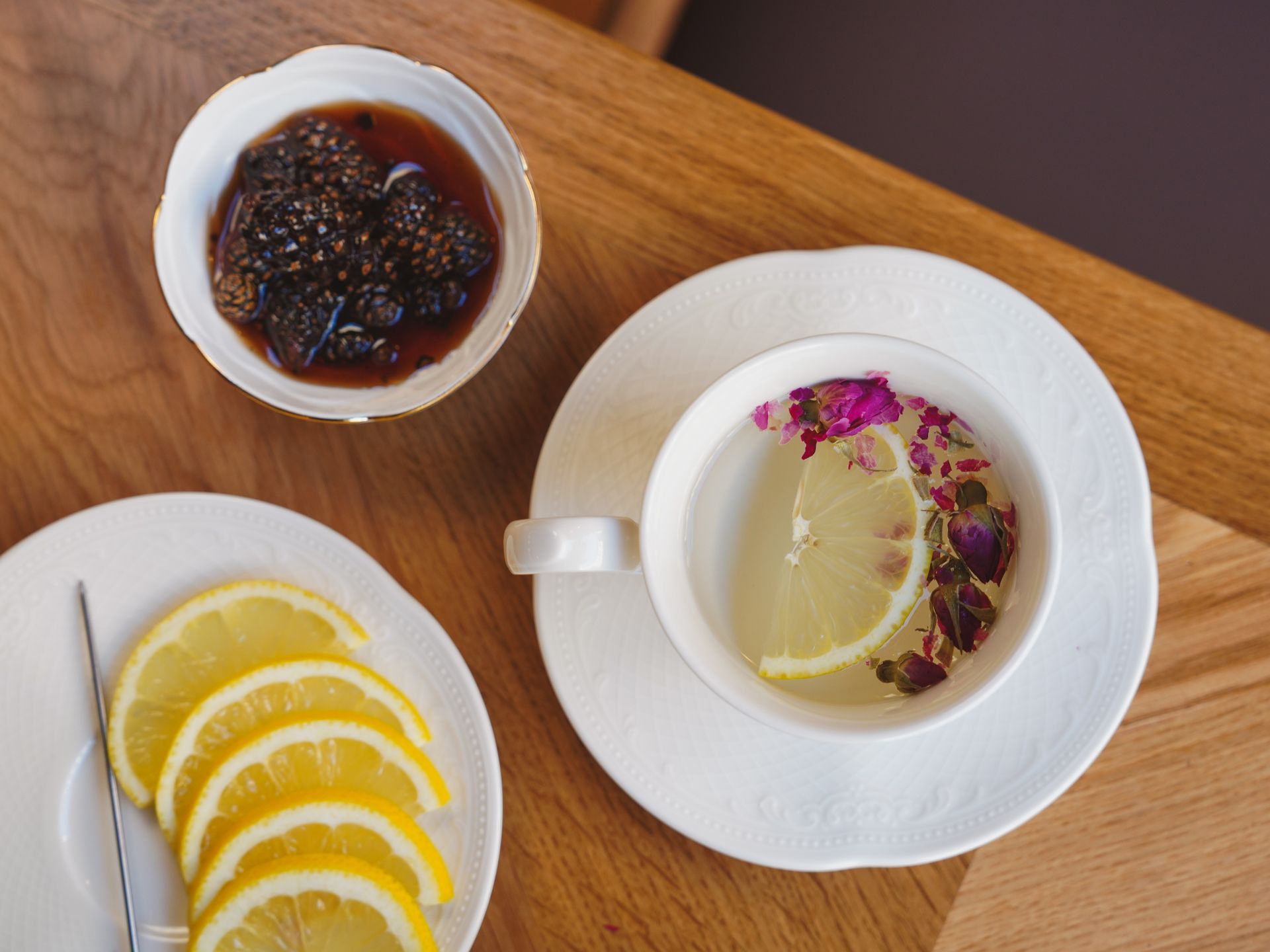 Elegant setup of lemon tea alongside fig jam and lemon slices on a wooden table.