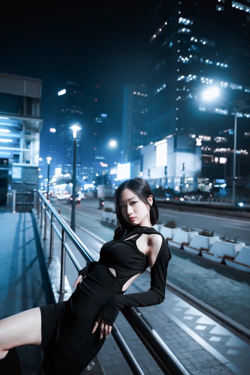 Young Woman in Dress Posing near Handrails in Night City