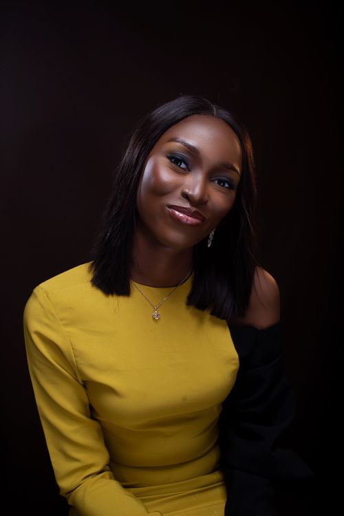 Free A striking portrait of a woman in a yellow dress against a black background, exuding confidence and elegance. Stock Photo