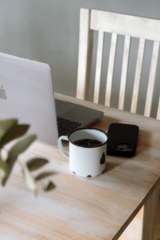 A minimalist workspace featuring a laptop, phone, and coffee mug on a wooden table.
