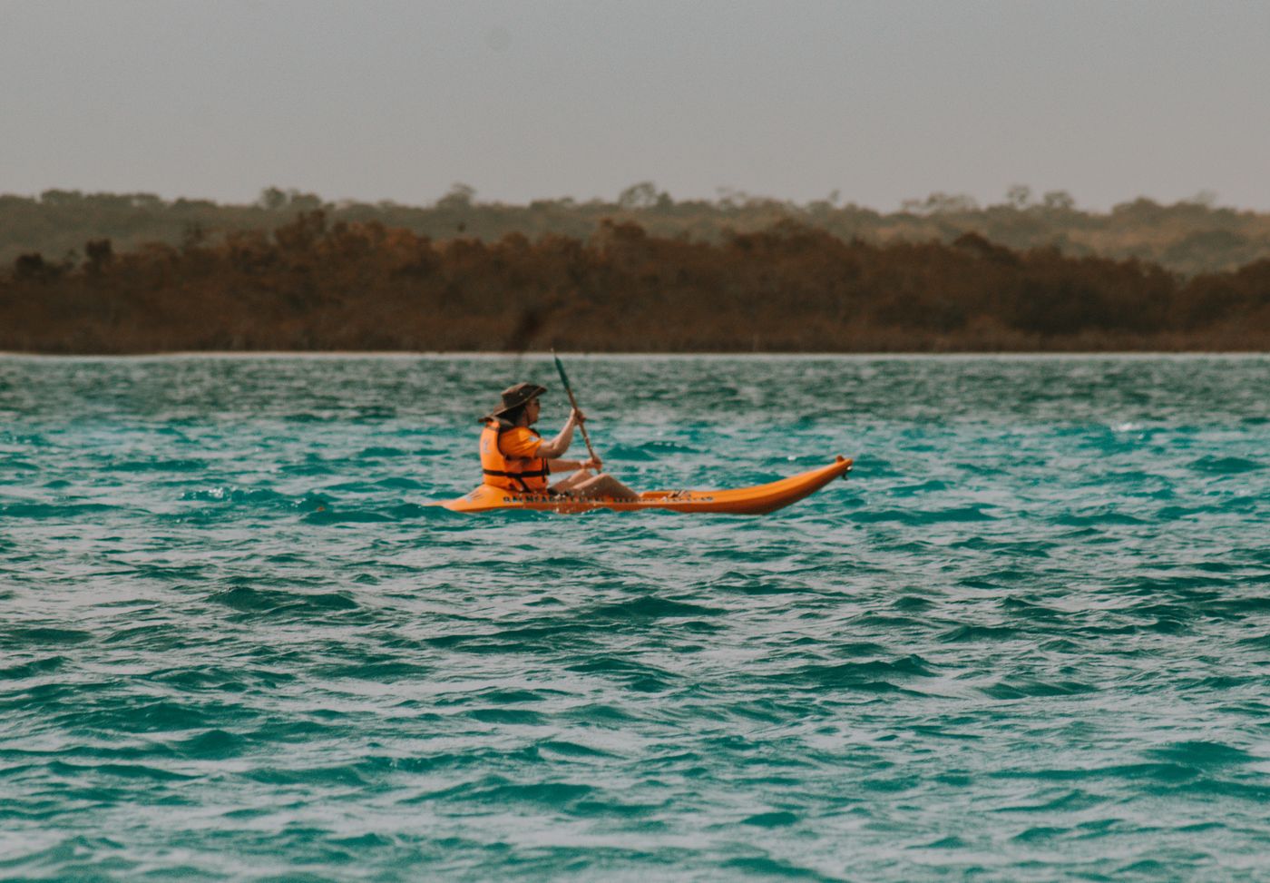 Paddler wearing a life jacket while kayaking on a clear lake