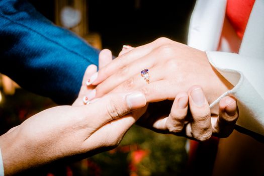 Close-up of hands during a romantic engagement proposal highlighting a beautiful ring.