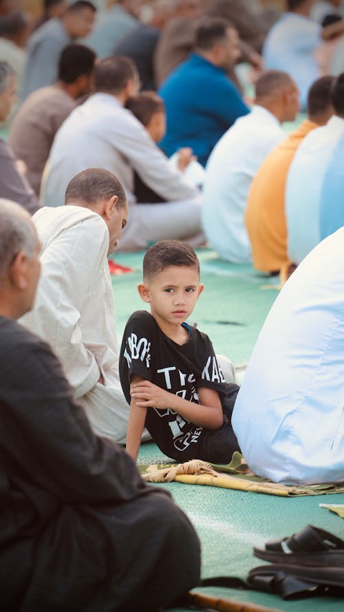 Boy Sitting Among People at Eid Mubark in Cairo, Egypt