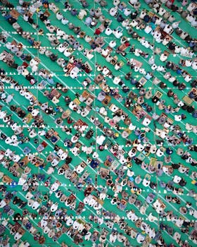 Top-down view of a large group of people praying in rows during Eid celebration outdoors.