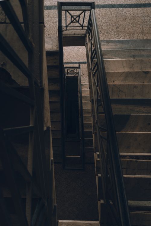 Free A dimly lit spiral staircase with intricate metal railings, creating an eerie mood. Stock Photo