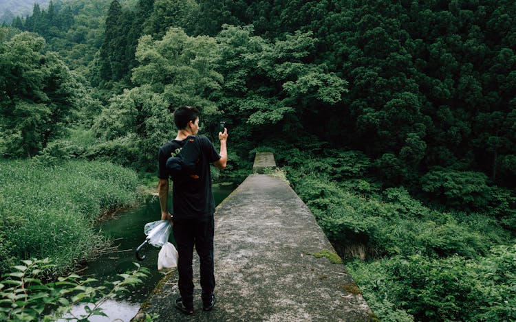 Man Taking Picture On Cellphone In Green Forest