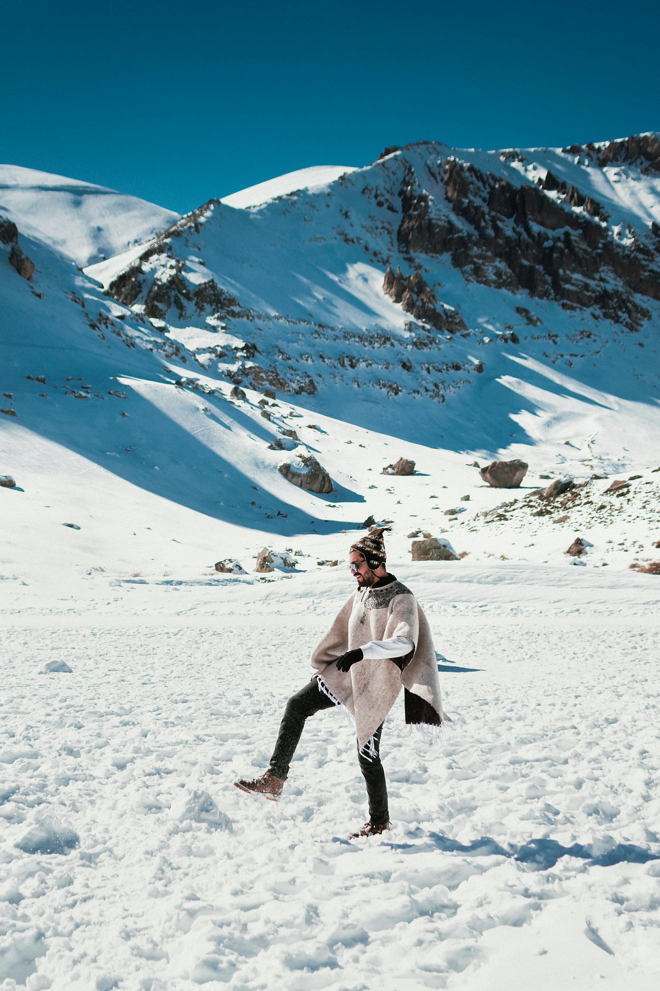 A man in warm clothing exploring the snowy Andes Mountains in Santiago, Chile.
