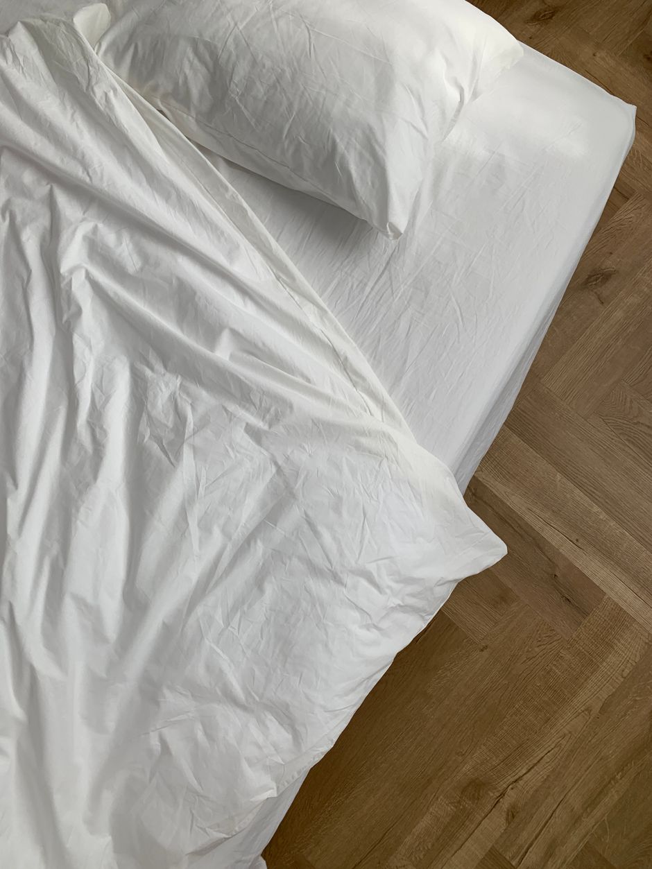 Cozy bedroom featuring a neatly made bed with white linens and a wooden floor.