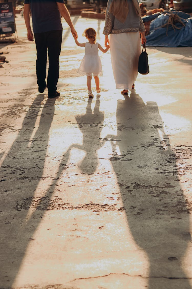 Family With A Little Girl Walking On A Street Hand In Hand