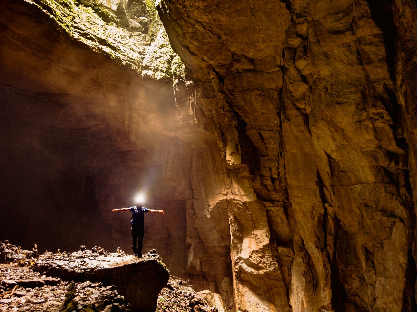 Man Standing inside a Rocky Cave with Spread Arms · Free Stock Photo