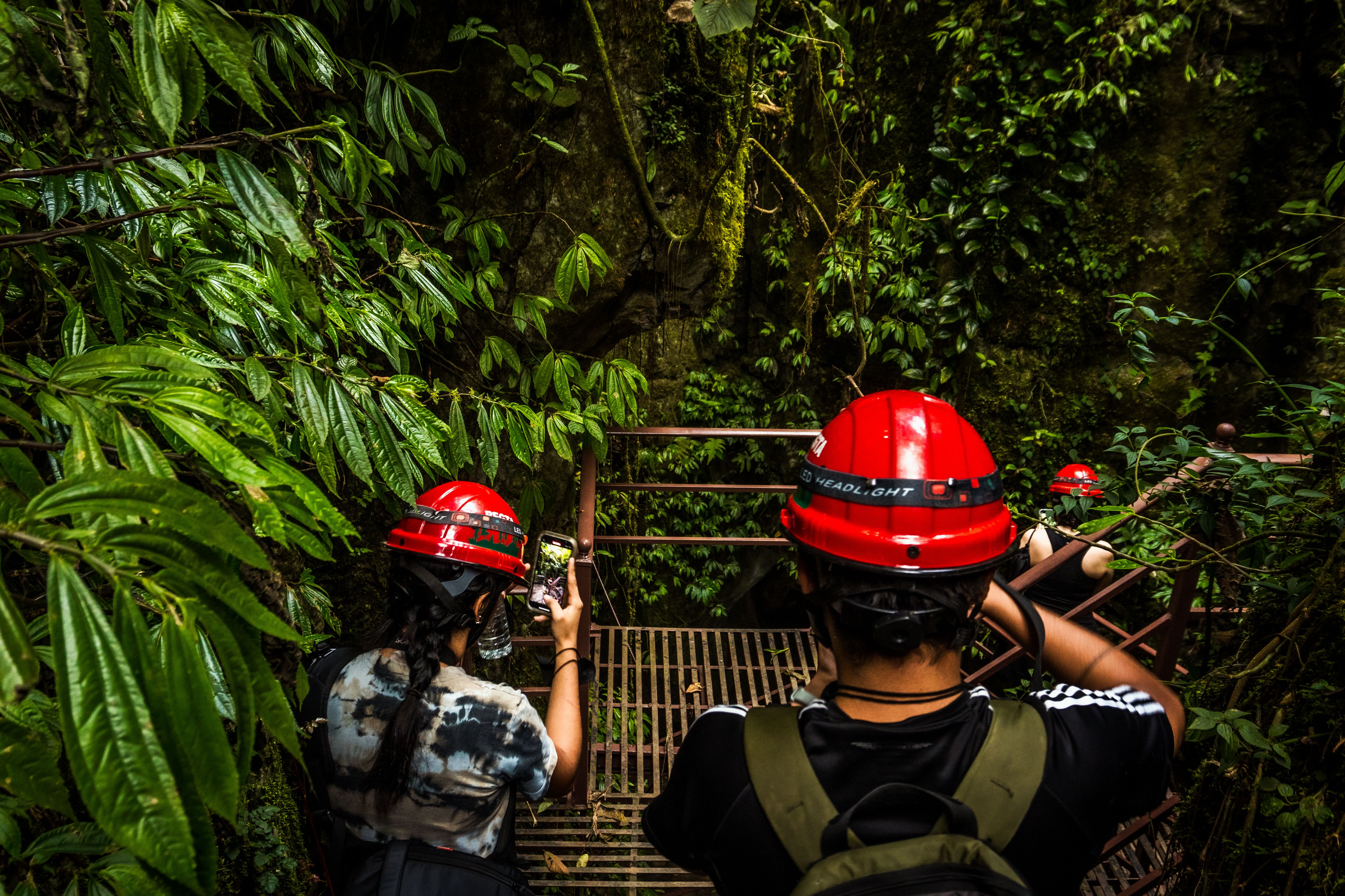 [ColoSach]-adventurers-wearing-helmets-descend-stairs-in-lush-jungle-of-cuetzalan,-mexico.