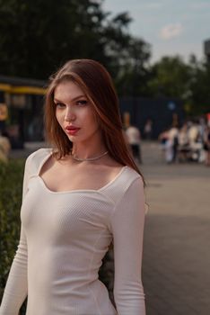 Portrait of a stylish woman in a white dress posing confidently outdoors in a city environment.