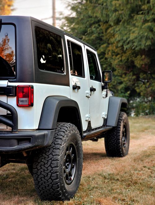 Free A rugged white Jeep Wrangler parked in a rural landscape, showcasing adventurous spirit. Stock Photo