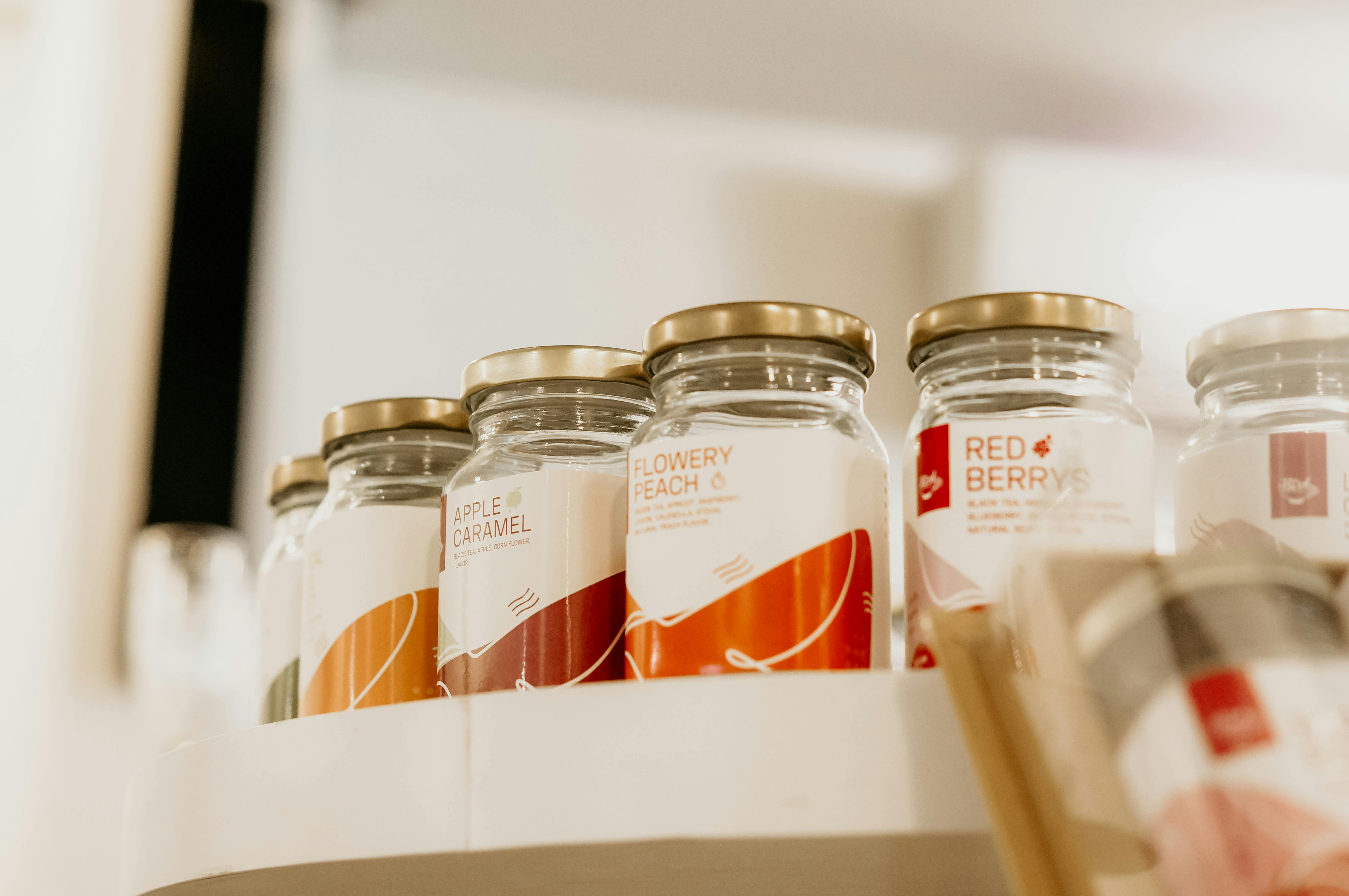 Clear Glass Jars With Labels On Open Shelving In A Kitchen