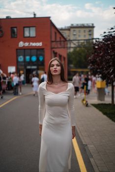 A stylish woman in a white dress poses confidently on a city street. Fashion and elegance.