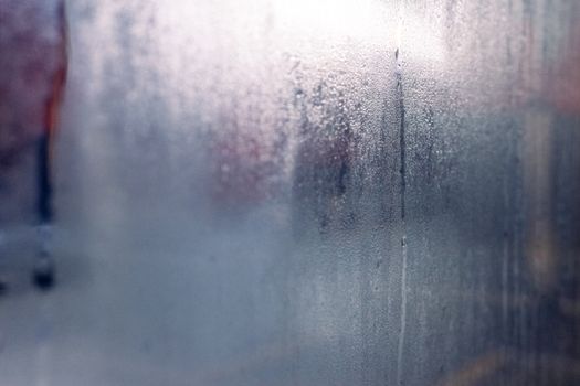 Moisture droplets on a foggy window create a mysterious and serene atmosphere.