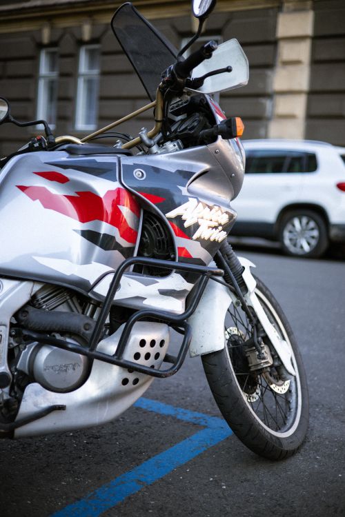 Free Close-up of a sleek silver motorcycle parked on a city street, capturing urban lifestyle. Stock Photo